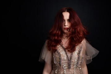 close up portrait of red haired  girl wearing a creamy fantasy gown like a fairy goddess costume.  isolated on dark studio background.
