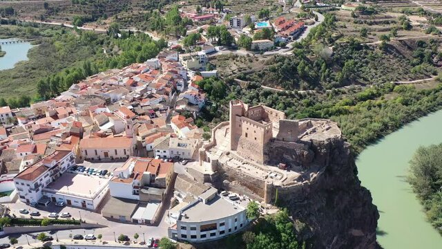 View from drone of Cofrentes cityscape and medieval castle on mountain plain at confluence of Jucar and Cabriel rivers on sunny fall day, Valencia, Spain. High quality 4k footage