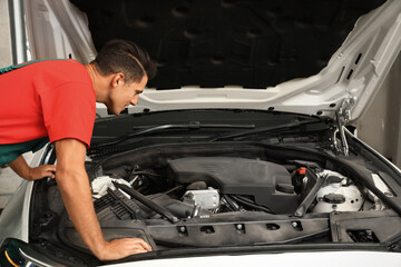Fototapeta na wymiar Professional mechanic checking modern car at automobile repair shop