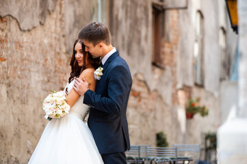 Beautiful young bride with wedding bouquet and groom near old castle before wedding ceremony