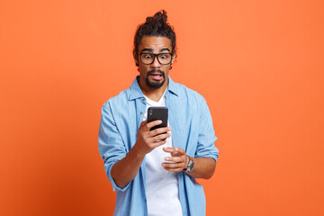 Shocked young african american man reading bad unexpected news on smartphone with opened mouth - obrazy, fototapety, plakaty