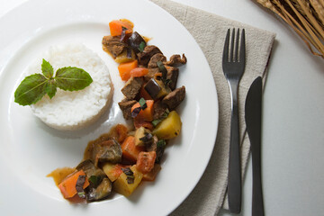Tiguadege na (Malian national dish) on a white plate with rice. Top view. Close up.