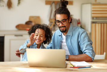 Happy positive african american family father and son enjoying video call on laptop at home