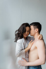 brunette woman in silk robe hugging shirtless man in bedroom