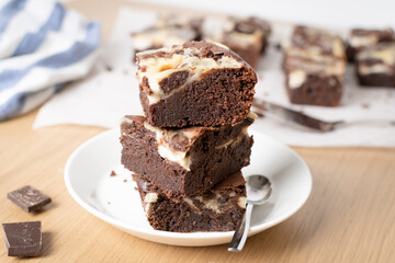 Freshly baked marbled chocolate brownies stacked on a plate
