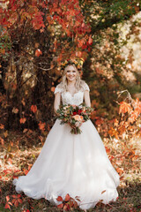 Obraz na płótnie Canvas blonde girl in a wedding dress in the autumn forest