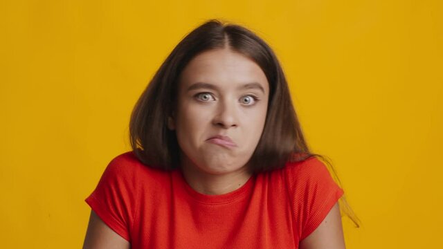 Clueless Woman Shrugging Shoulders Posing Over Yellow Studio Background