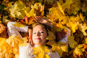 Woman laying in maple leaves in the park.