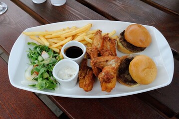 Dinner platter consisting of burger sliders, chicken wings, fish and chips goujons, seasoned fries, BBQ sauce and tartar sauce in Salisbury, UK