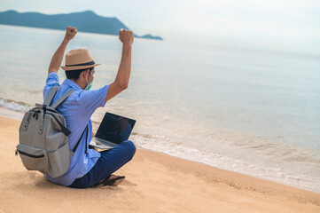 Man wear mask using laptop computer on beach  sea  and Man travel holiday Phuket sandbox Thailand are freedom life financial