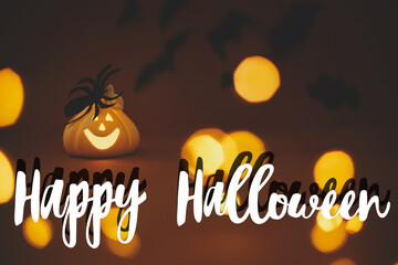 Happy Halloween text sign on glowing jack o lantern pumpkin with spider on dark orange background...