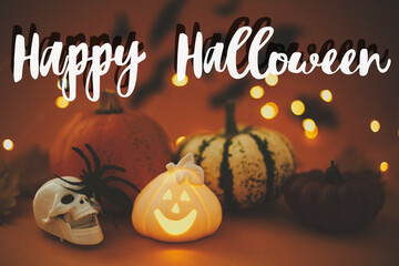 Happy Halloween text sign on pumpkins, glowing jack o lantern,  spider, skull on dark orange...