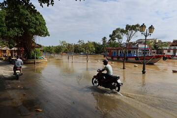 Hoi An, Vietnam, October 25, 2021: Two motorcycles drive down a flooded street in downtown Hoi An,...
