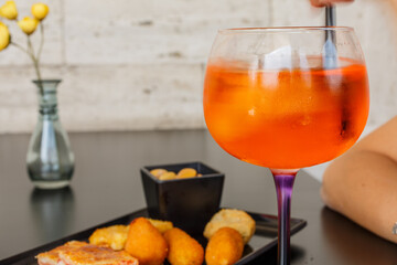 Cocktail di colore arancione mentre viene mescolato con una cannuccia nera