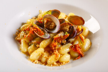 Gnocchi di patate con vongole veraci e fiori di zucca serviti come primo piatto in un ristorante