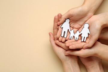 People holding paper family cutout on beige background, top view. Space for text