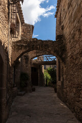 Fototapeta na wymiar narrow stone street with an arch in the medieval village of pals on a summer day