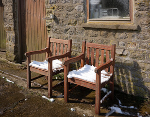 Fototapeta na wymiar Wooden garden chairs dry in April sun after unexpected spring snowfall