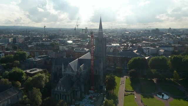 Orbit around St Patricks Cathedral against sunshine. Many cranes helping on constructions. Dublin, Ireland