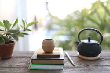 Bamboo wooden cup and books with old black metal teapot