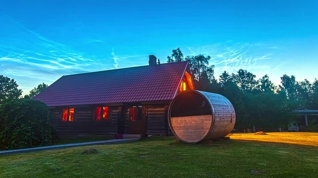 People living inside Wooden Cottage with Barrel Sauna during holiday trip - Blue sky with flying clouds - Vibrant constrast colors of time lapse footage
