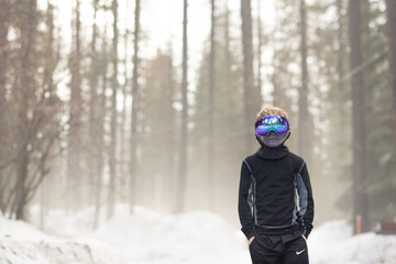 Fototapeta na wymiar Boy in Goggles in the snowy white trees forest 