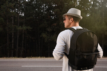 Man with backpack on road near forest