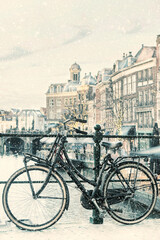 Fototapeta na wymiar Winter view with snowfall of the Dutch Nieuwe Rijn canal with bridge and bicycle in the city center of Leiden