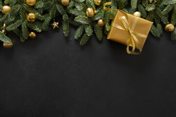 Christmas golden gift and evergreen branches on black background with copy space. Xmas festive...