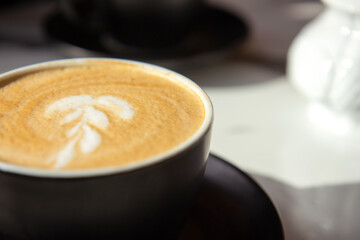 Black ceramic cup of coffee on a marble table on an open terrace in bright sunlight