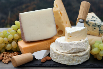 Fototapeta premium Different types of delicious cheeses and snacks on wooden table outdoors