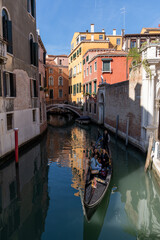gondola with tourists travelling through the narrow canals of the old town of Venice