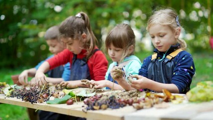 forest kindergarten. Happy Preschool or school group children play sculpt clay in swamp in park or forest. Outdoors small child have fun playing with mud. Summer Camp curious, kid leisure in nature - Powered by Adobe