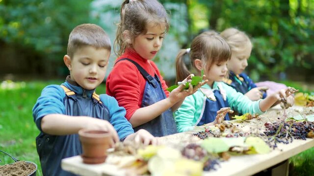 forest kindergarten. Happy Preschool or school group children play sculpt clay in swamp in park or forest. Outdoors small child have fun playing with mud. Summer Camp curious, kid leisure in nature