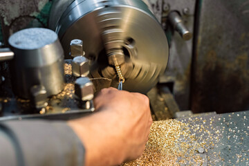 The turner cuts the bronze hexagon blanks on the lathe.