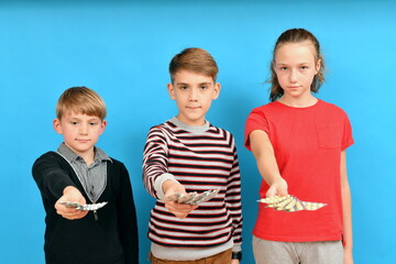 Three children hold out their hands with medicines and show pills.