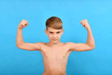 A small thin boy without muscles raised his arms to the top and shows biceps. Lean and skinny...