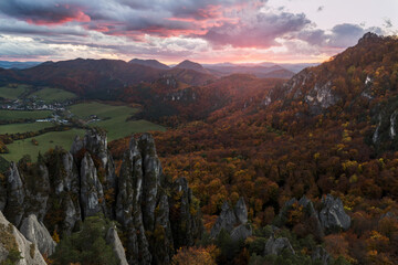Fototapeta na wymiar Scenic landscape in Sulov, Slovakia, on beautiful autumn sunrise with colorful leaves on trees in forest and bizarre pointy rocks on mountains and slight mist in the valleys and dramatic clouds on sky