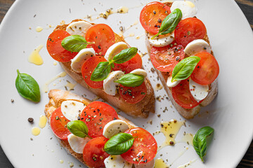 bruschetta caprese. fresh basil leaves, ripe aromatic tomatoes and Italian mozzarella on bruschetta, drizzled with olive oil and sprinkled with pepper and herbs.