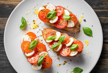bruschetta caprese. fresh basil leaves, ripe aromatic tomatoes and Italian mozzarella on bruschetta, drizzled with olive oil and sprinkled with pepper and herbs.