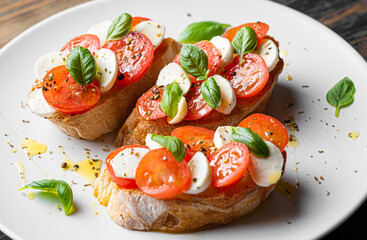bruschetta caprese. fresh basil leaves, ripe aromatic tomatoes and Italian mozzarella on bruschetta, drizzled with olive oil and sprinkled with pepper and herbs.