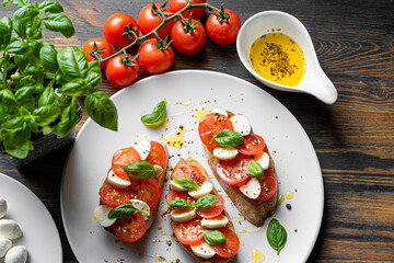 bruschetta caprese. fresh basil leaves, ripe aromatic tomatoes and Italian mozzarella on bruschetta, drizzled with olive oil and sprinkled with pepper and herbs.