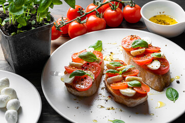 bruschetta caprese. fresh basil leaves, ripe aromatic tomatoes and Italian mozzarella on bruschetta, drizzled with olive oil and sprinkled with pepper and herbs.