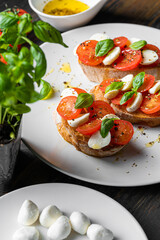 Fototapeta na wymiar bruschetta caprese. fresh basil leaves, ripe aromatic tomatoes and Italian mozzarella on bruschetta, drizzled with olive oil and sprinkled with pepper and herbs.