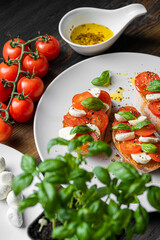 bruschetta caprese. fresh basil leaves, ripe aromatic tomatoes and Italian mozzarella on bruschetta, drizzled with olive oil and sprinkled with pepper and herbs.