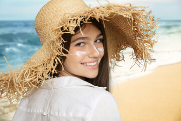 Teenage girl with sun protection cream on her face near sea