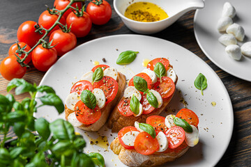 bruschetta caprese. fresh basil leaves, ripe aromatic tomatoes and Italian mozzarella on bruschetta, drizzled with olive oil and sprinkled with pepper and herbs.