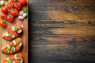 bruschetta caprese. fresh basil leaves, ripe aromatic tomatoes and Italian mozzarella on bruschetta, drizzled with olive oil and sprinkled with pepper and herbs.