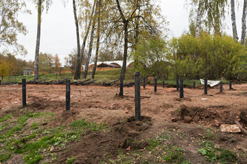 Fototapeta na wymiar At the construction site. Foundation piles. Some of the piles are already in the ground, some of the piles have not yet been driven into the ground. Foundation installation process. Modern