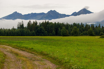 Landscape of the High Tatras mountain range in the early morning with a fog cloud passing by,...